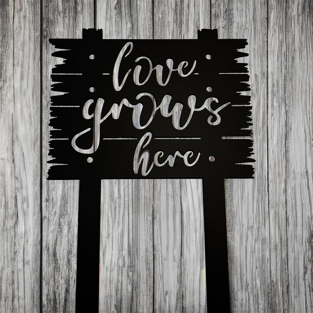 Love Grows Here Sign with Stakes on gray wood background