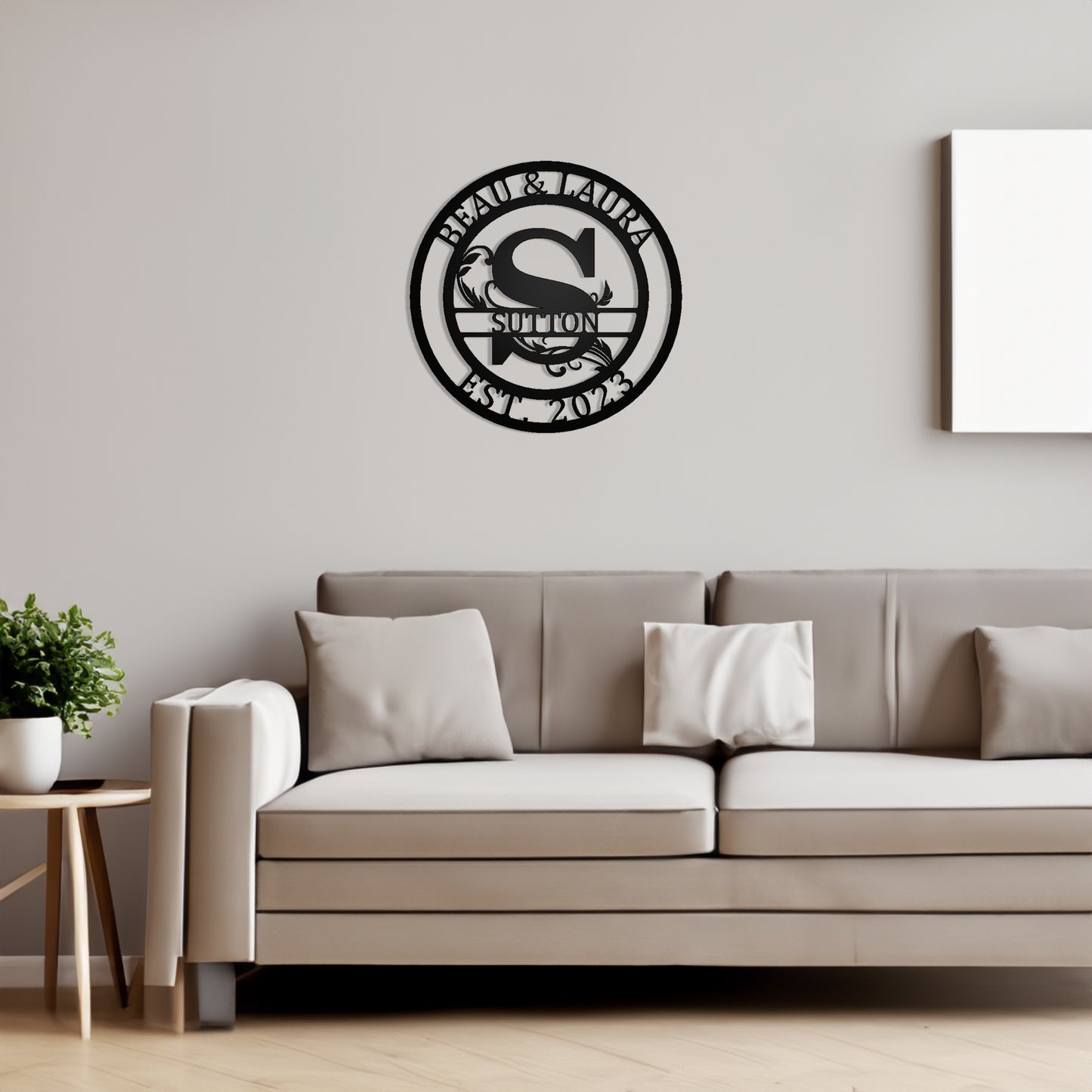 Round Scroll Monogram with Top Personalization and EST Date black S with "BEAU & LAURA SUTTON 2023" personalization on a wall in a living room