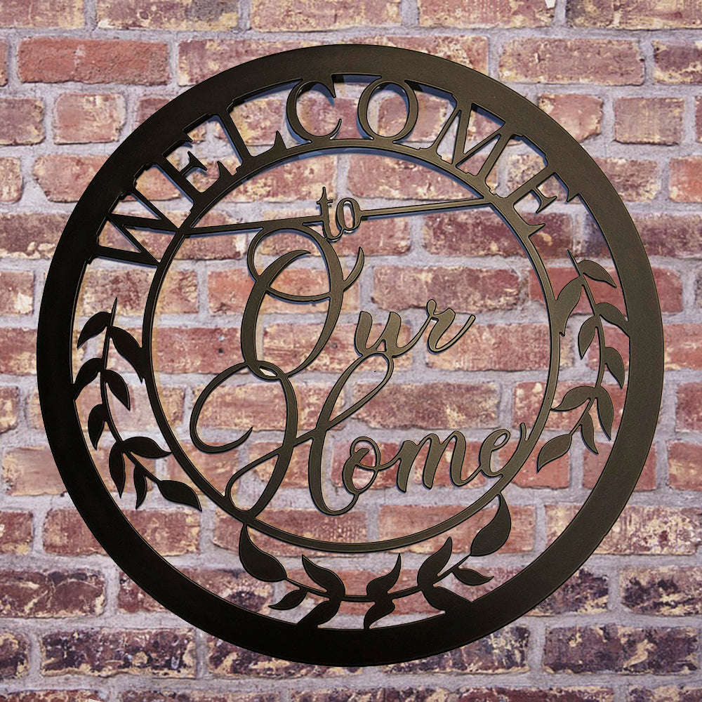 Welcome to Our Home Round Metal Sign Black on brick wall background