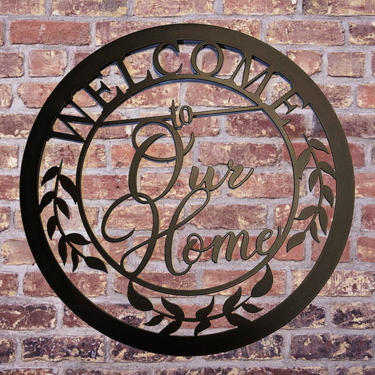 Welcome to Our Home Round Metal Sign Black on brick wall background
