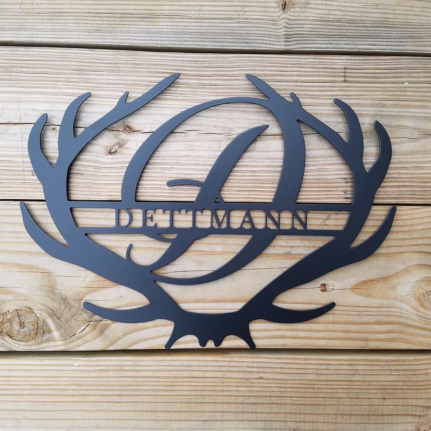 Antler Rustic Family Name Monogram Metal Sign on a wood deck background